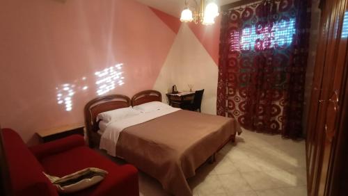 a bedroom with a bed and a red chair at Angis AffittaCamere in Pero