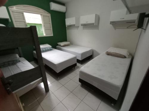 um quarto com três camas e uma janela em Hostel Office- Hospedagem Climatizada quartos e apartamentos privativos em Extrema