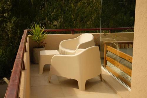 a balcony with white chairs and a plant at Arena de Mar Depto F in Mar de las Pampas