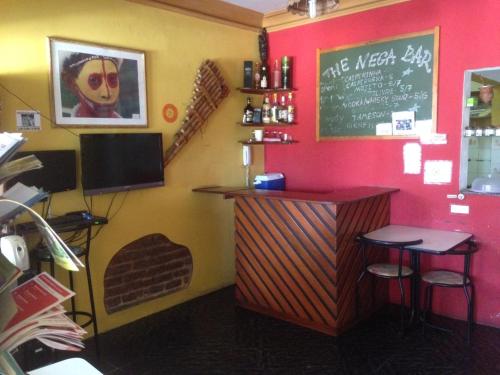 a restaurant with a bar with two stools and a chalkboard at Nega Maluca Guesthouse in Salvador