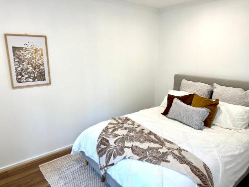 a bedroom with a bed with white sheets and pillows at Guest house on the park in Burwood East
