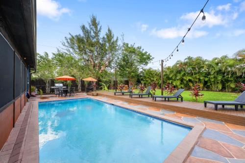 a swimming pool in a yard with benches at Unique super cozy,Bohemian Paradise with Heated Pool and positive energy in Pompano Beach
