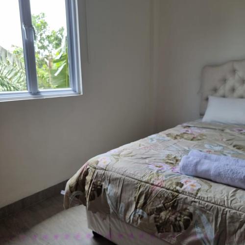 1 dormitorio con 1 cama junto a una ventana en Rumah Tropis - Lantai Dasar en Parit