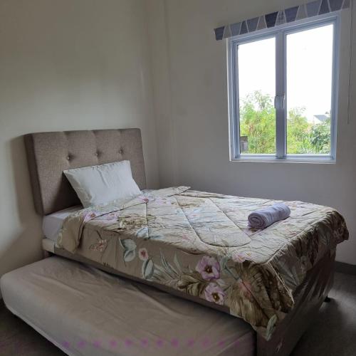 1 cama en un dormitorio con ventana en Rumah Tropis - Lantai Dasar en Parit