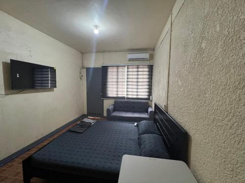 een kamer met een bed, een bank en een tv bij Yna's Place - The Fourth House in Balintiouac