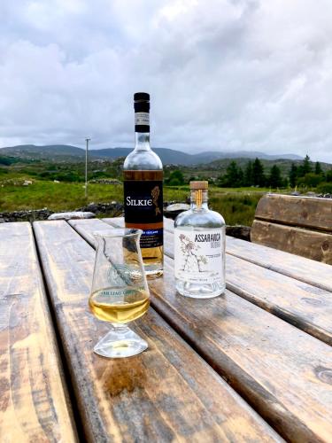 a bottle of wine and a glass on a wooden table at Beautiful Donegal Thatched Adderwal Cottage with Hot Tub in Doochary