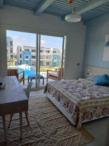 a bedroom with a bed and a view of a pool at Fouka Bay North Coast 2BRs Modern Style Serviced Apartment with Open Pool & Sea View in Marsa Matruh