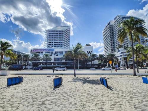 a beach with chairs and palm trees and buildings at 1201 W Residences in Fort Lauderdale
