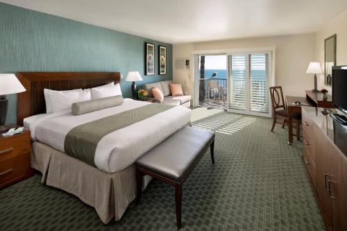 a bedroom with a large bed and a living room at Shore Cliff Hotel in Pismo Beach