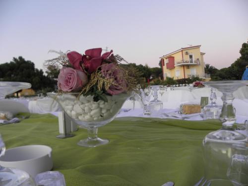 a table with a glass vase with flowers in it at Irida Beach Resort Suites in Kyparissia