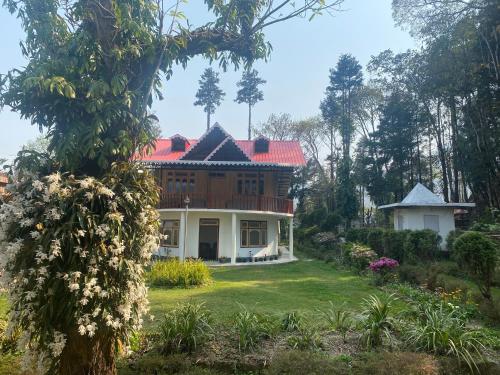 a house with a red roof in a garden at Bloomfield Farmhouse and Eco-Resort in Darjeeling