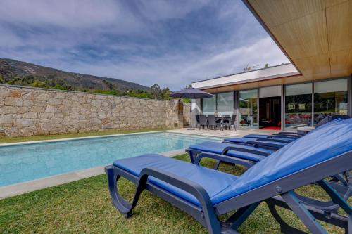 a group of blue lounge chairs next to a swimming pool at Casa do Poço in Caminha