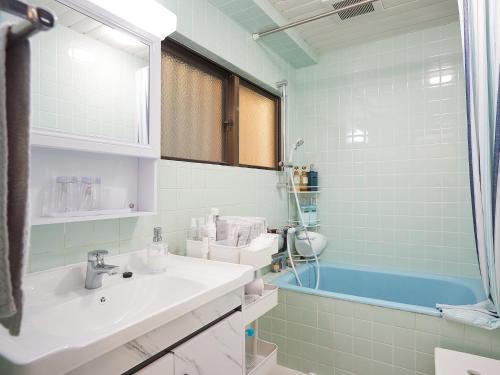 ein Badezimmer mit einem Waschbecken und einer Badewanne in der Unterkunft Guest house II Rokumarukan in Naha