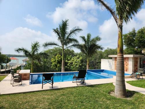 a swimming pool with chairs and a palm tree at Quinta La Calma in La Pesca