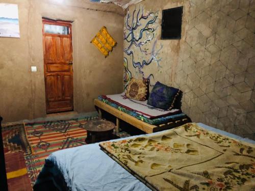 a bedroom with a bed and a table and a door at Desert skay camp in Mhamid