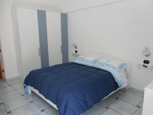 a bed in a white room with a blue blanket at Da Zia Pina in Minori