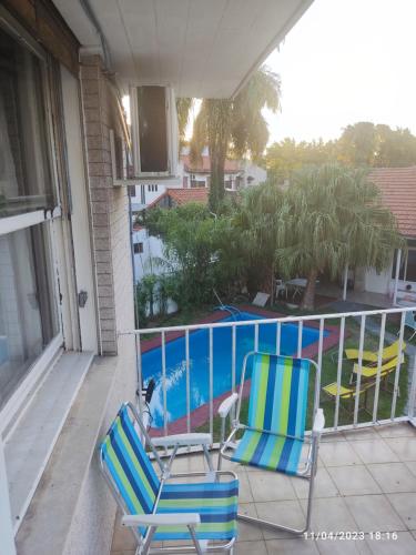 two chairs on a balcony with a swimming pool at hostel olivos in Olivos