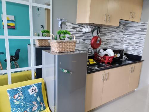 eine Küche mit einem Kühlschrank und einem gelben Stuhl in der Unterkunft Stylish New Unit w/ Balcony at Fern Residences in Manila