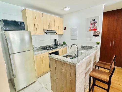 a kitchen with a stainless steel refrigerator and wooden cabinets at Casa Sol Apartamento vista al mar cerca del aeropuerto y Miraflores in Lima