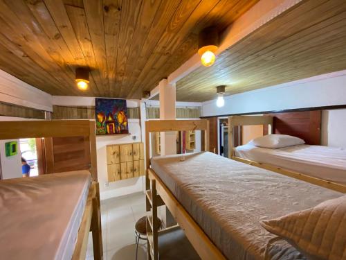 a bedroom with two beds and a wooden ceiling at Zicatela Beach Hostel in Pipa