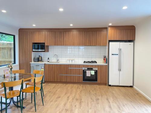 a kitchen with a table and a white refrigerator at NO PARTY ALLOWED, Entire Brand New 3 bedroom townhouse, free unlimited fibre wifi and free parking in Wellington