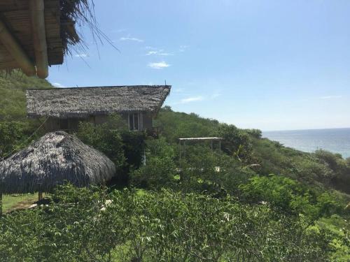 Santa MarianitaにあるCasa Las Mantasの海の近くの丘の上にある藁葺き屋根の家