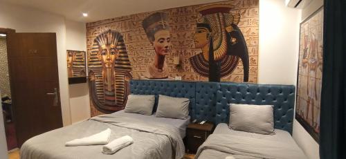 1 dormitorio con 2 camas y un cuadro en la pared en Grand Pyramids In en Giza