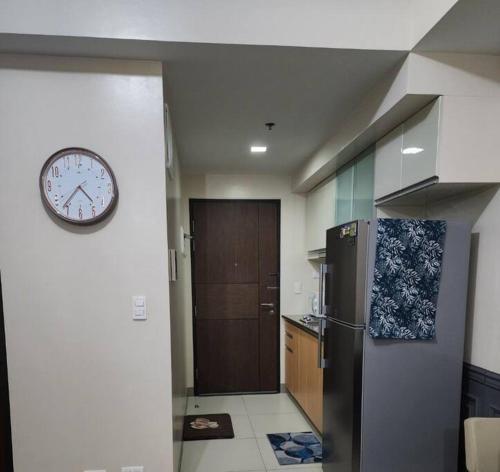 a kitchen with a clock on the wall and a refrigerator at Cozy Studio Unit near Uptown Mall BGC in Manila