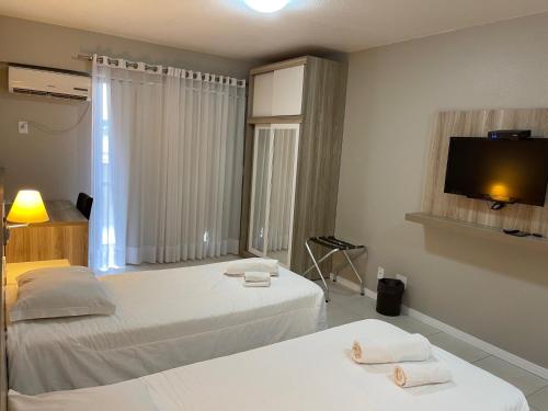 a bedroom with two beds and a flat screen tv at Aquarius Flat Studio 509 in Santa Cruz do Sul