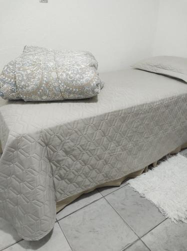 uma cama com um edredão cinzento e uma almofada em Casa Penedo em Itatiaia