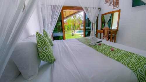 a bedroom with a white bed with green and white pillows at Bali Dyana Villas in Seminyak