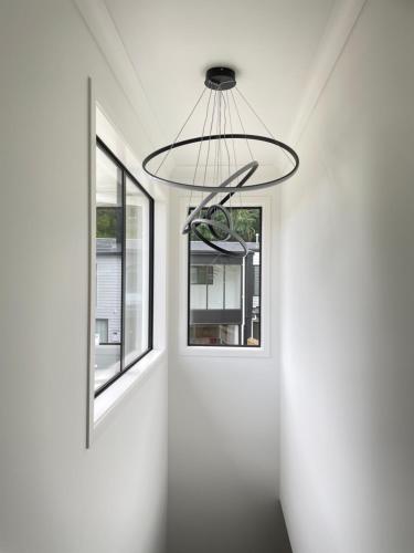 a room with two windows and a chandelier at NO PARTY ALLOWED, Entire Brand New 3 bedroom townhouse, free unlimited fibre wifi and free parking in Wellington