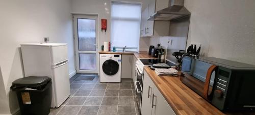 a small kitchen with a washer and dryer in it at Warwick St by Prestige Properties SA in Barrow in Furness