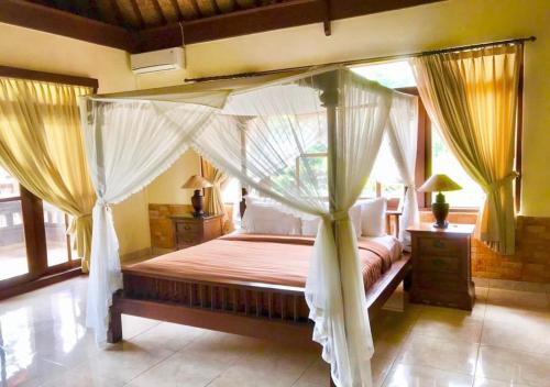 sypialnia z łóżkiem z baldachimem i zasłonami w obiekcie Pande Permai Bungalows w mieście Ubud
