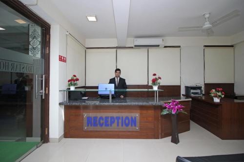 a man sitting at a reception desk in an office at Flagship 9046 Hotel Metro Star in New Delhi