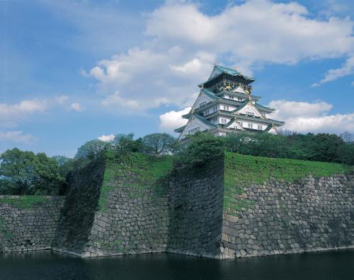 a castle on top of a stone wall with a tower at Sotetsu Grand Fresa Osaka-Namba in Osaka