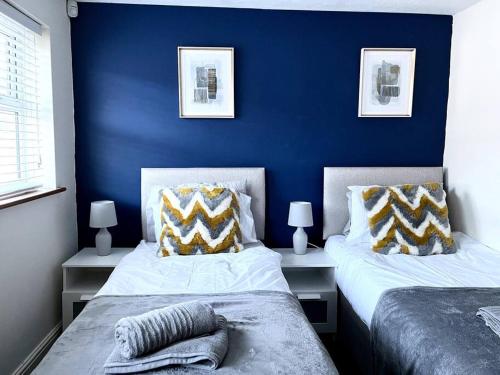 twee bedden in een slaapkamer met een blauwe muur bij Central Semi - Detached Home with Private Parking! in Buckinghamshire