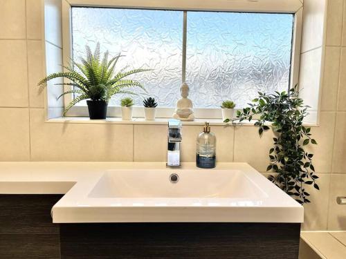a white sink in a bathroom with a window at Central Semi - Detached Home with Private Parking! in Buckinghamshire