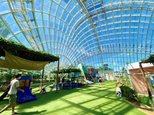 a large glass domed building with people in a playground at hanare in Yamanashi