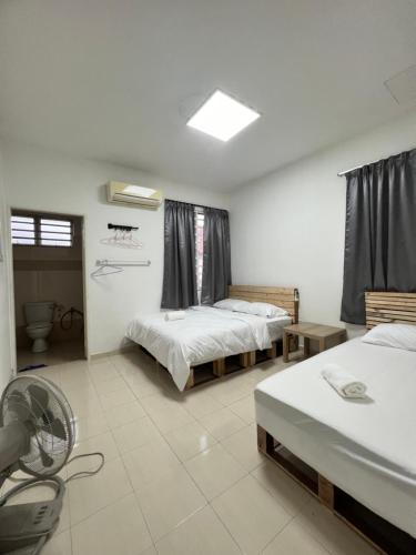 a room with two beds and a fan in it at Icon BM Vacation Home with Water Fountain and Barbeque Area by ZamanJa in Bukit Mertajam