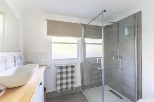 a bathroom with a glass shower stall and a sink at Myrtle Creek Cottage in Myrtleford