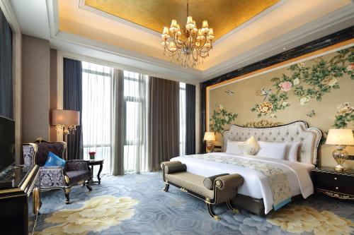 a bedroom with a large bed and a chandelier at Wanda Realm Bozhou in Bozhou