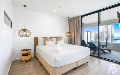 una camera con un grande letto bianco e un balcone di The Wave - QStay a Gold Coast