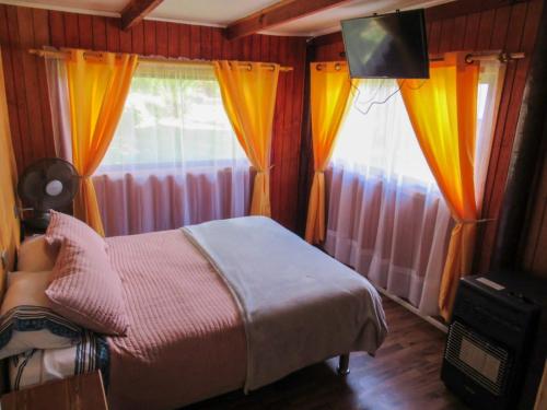 a bedroom with a bed and two windows with curtains at CABAÑAS LOS CASTAÑOS in Los Ángeles