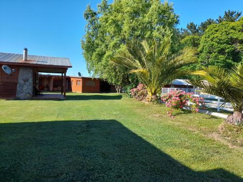 une cour avec une maison, des palmiers et de l'herbe dans l'établissement CABAÑAS LOS CASTAÑOS, à Los Ángeles