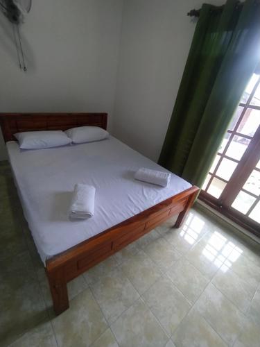 a bedroom with a bed with white sheets and a window at Janaka's House in Dickwella