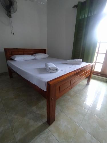 a bed with a wooden frame in a room at Janaka's House in Dickwella