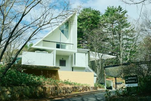 une maison blanche sur le côté d'une route dans l'établissement Fourtreat Kusatsu, à Kusatsu