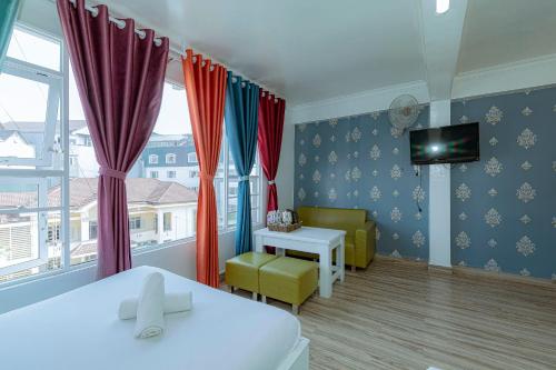 a room with a bed and a table and a tv at Ken's Backpackers Hotel in Da Lat