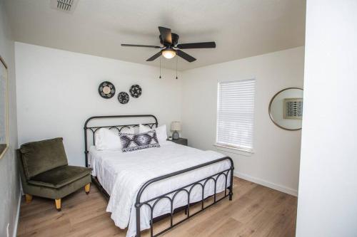 1 dormitorio con 1 cama, ventilador de techo y silla en 7 beds Relax by Texas Tech & Hospitals Sleeps 10, en Lubbock